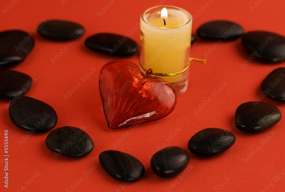 candle, river stones and red heart on red background