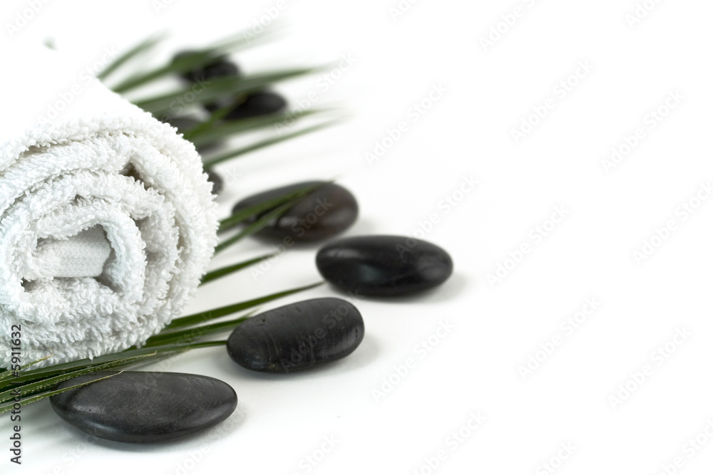 Eight pebbles, towel and palm leaf over white. Selective focus.