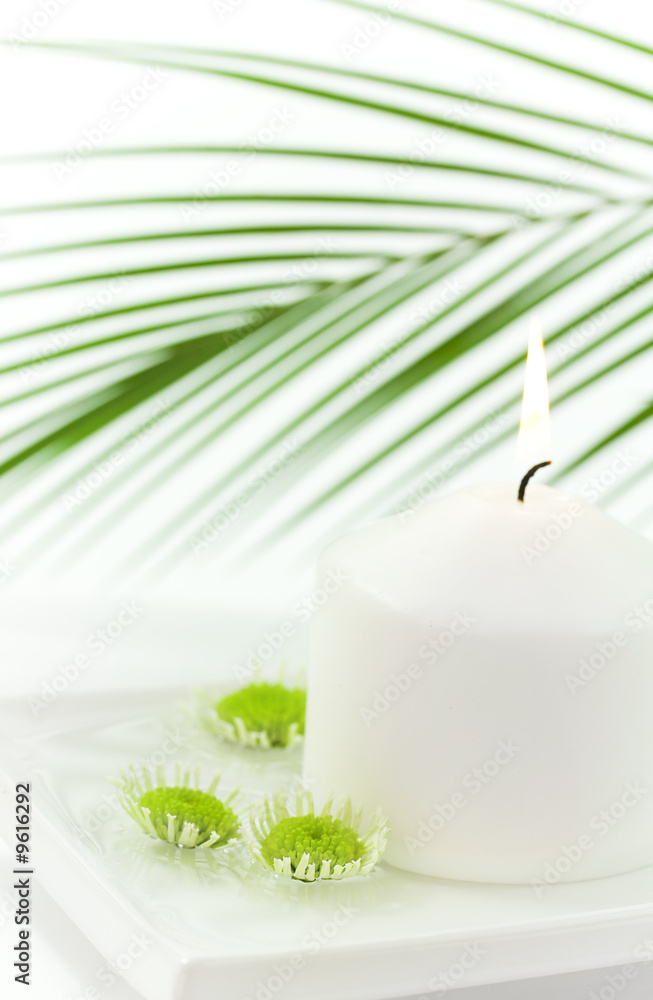 White candle and floating green flowers. Selective focus.