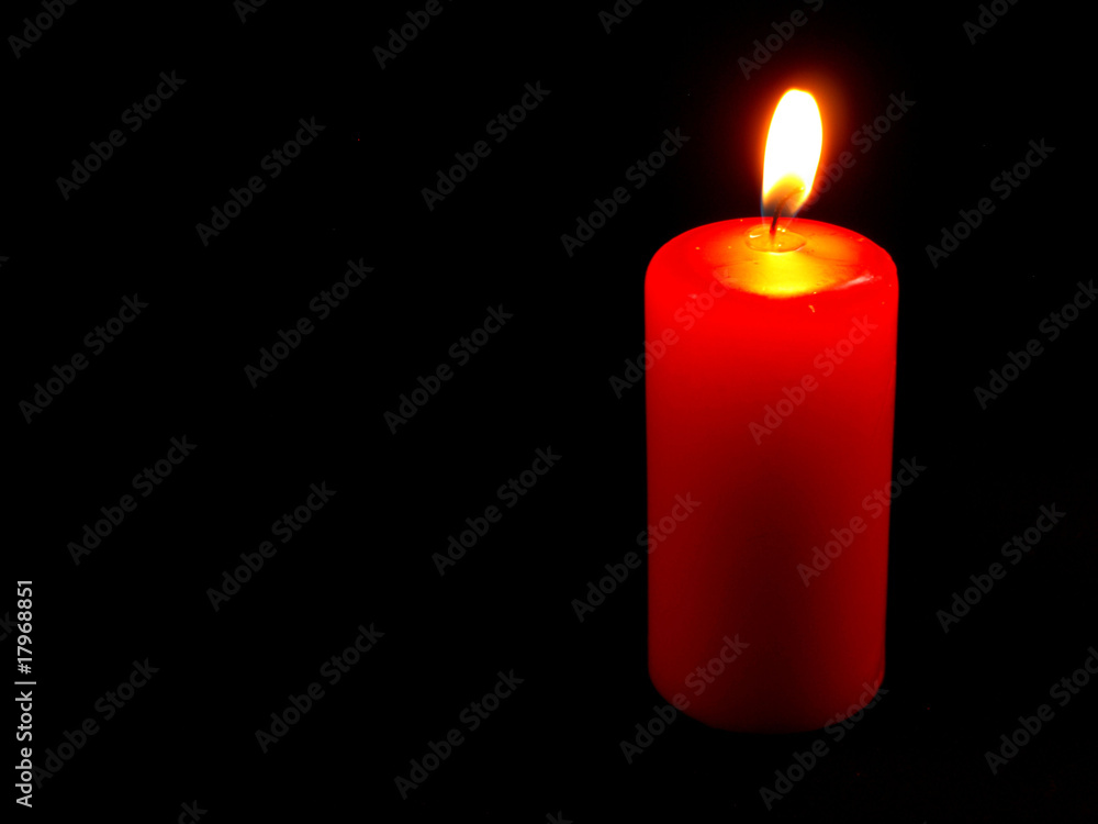 Burning candle on black background