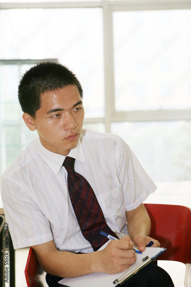 young asian businessman sitting on desk in office