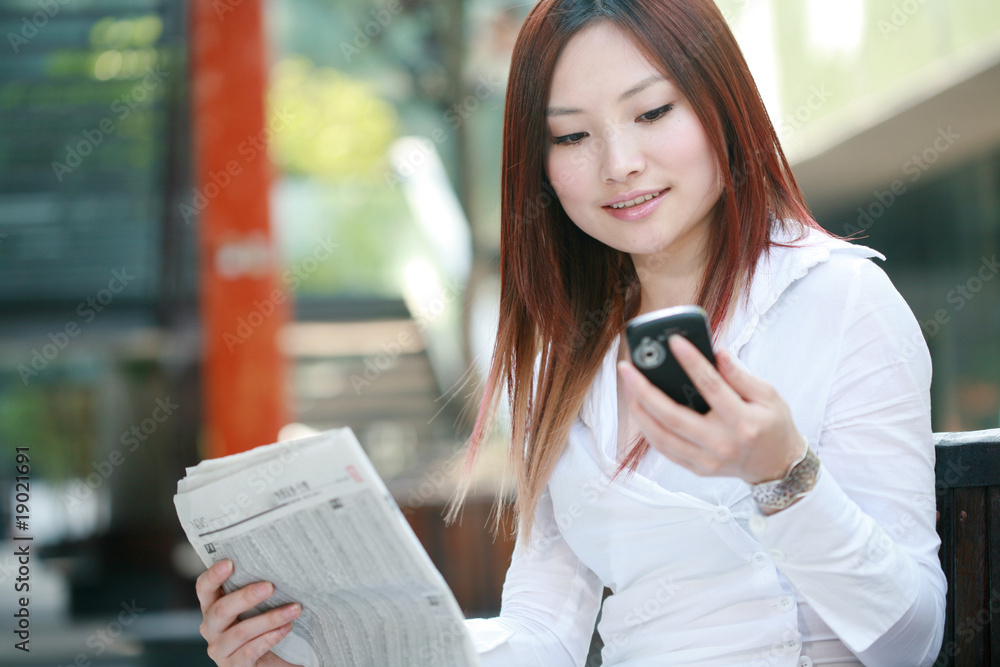 businesswomen reading newspaer and holding mobile