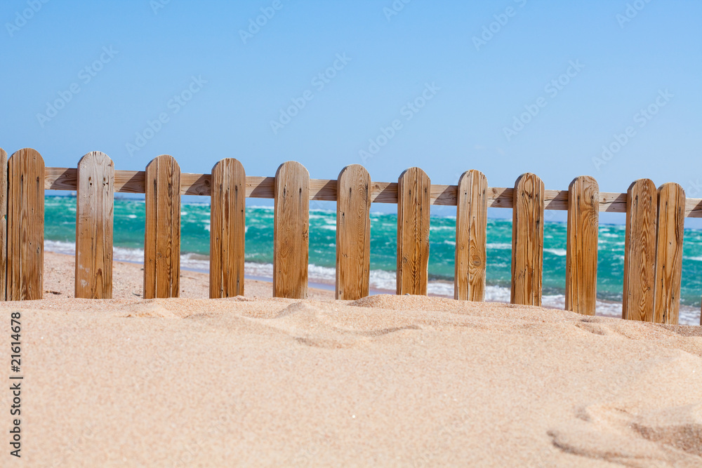 Small wood fence in sand on the coast