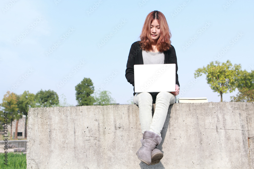 亚洲女孩与笔记本电脑户外