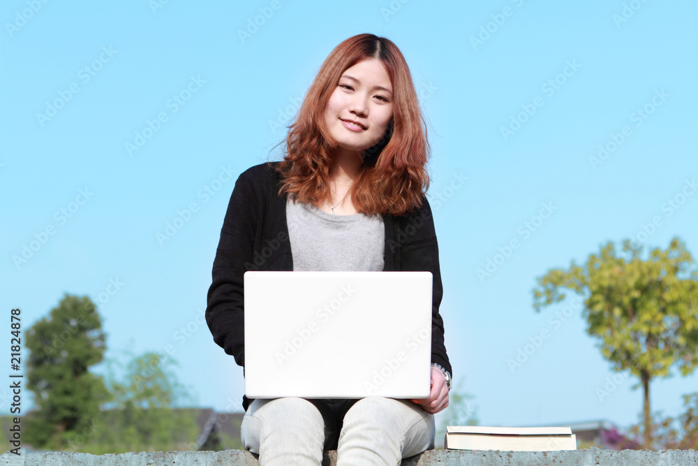 亚洲女孩与笔记本电脑户外