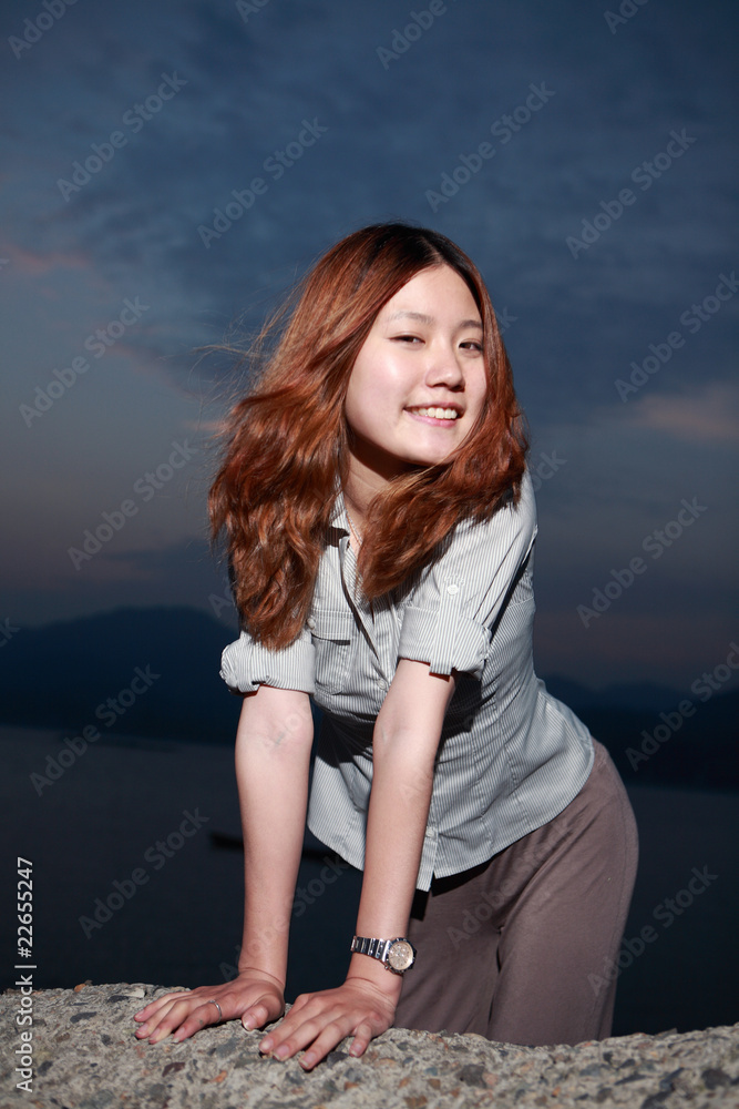 Beautiful young woman on the beach at sunset .