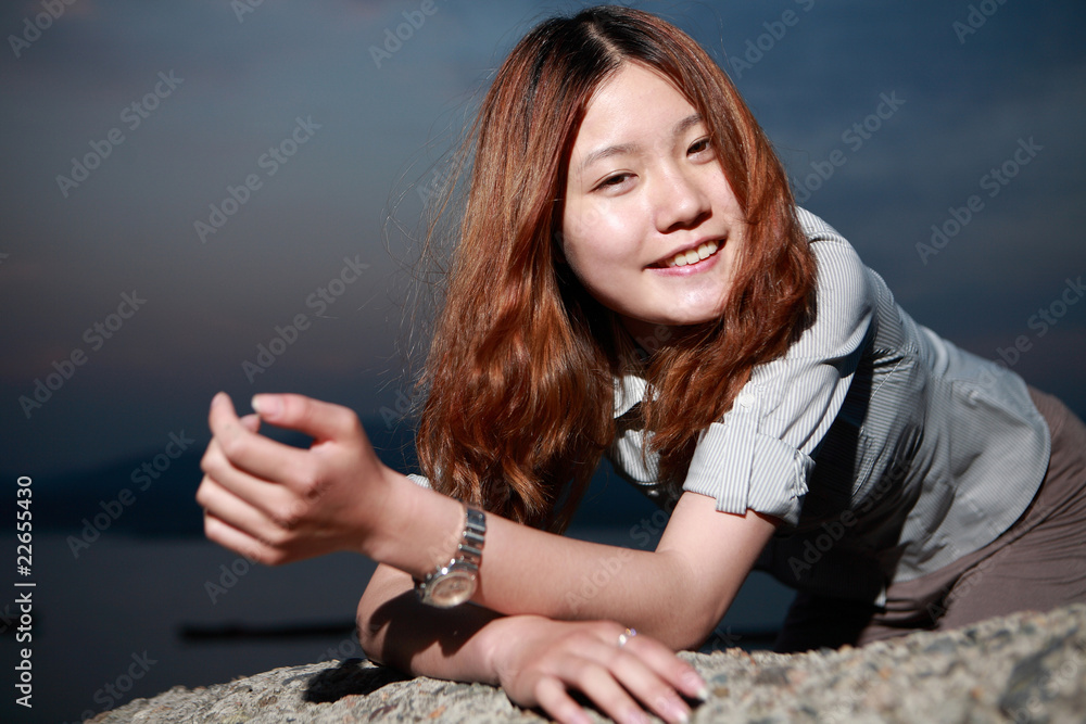 Beautiful young woman on the beach at sunset .