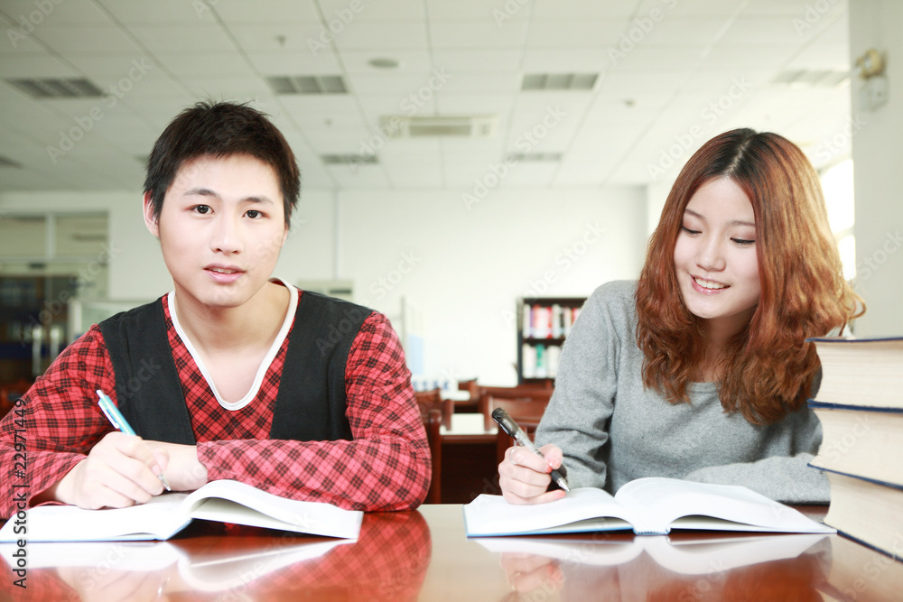 在图书馆学习的亚洲男孩和女孩