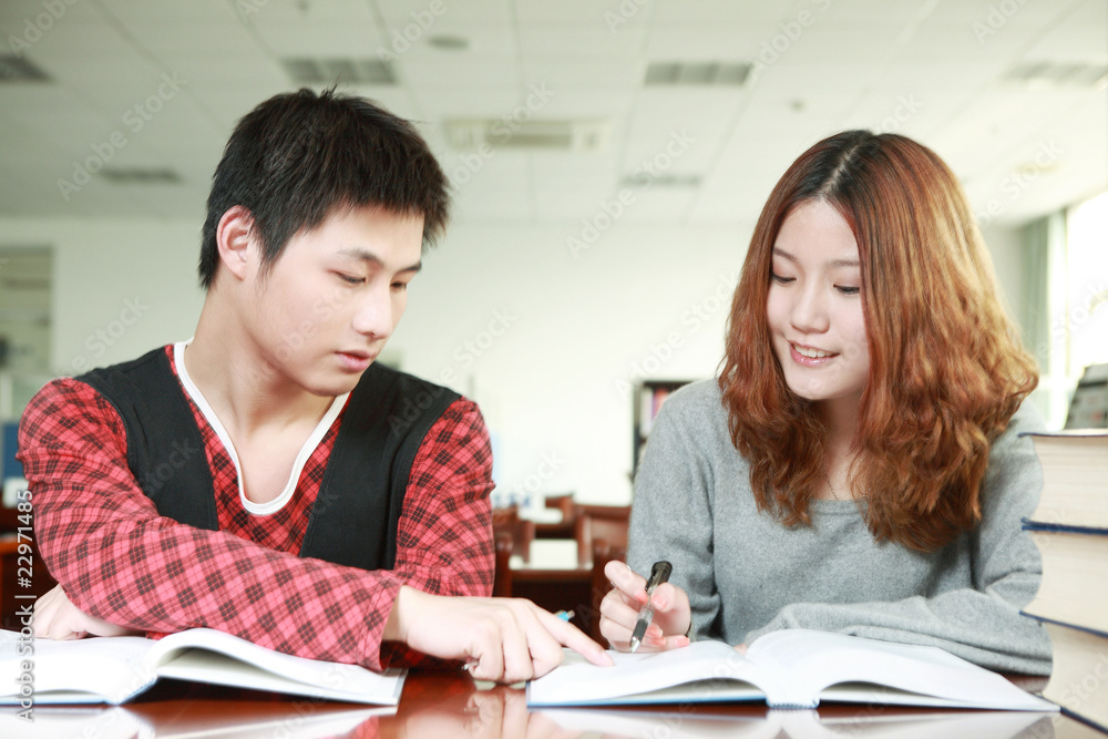 在图书馆学习的亚洲男孩和女孩