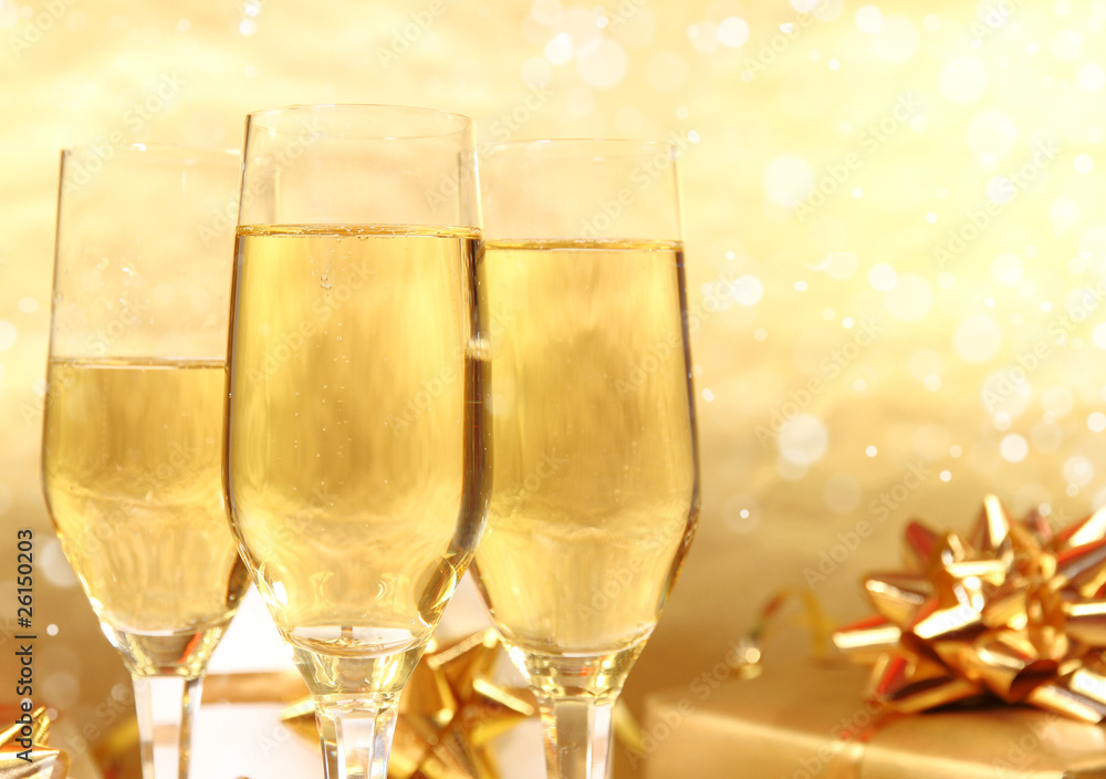 Glasses of champagne with golden decoration on background