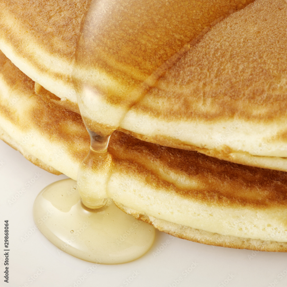 Pancakes with honey on white plate.