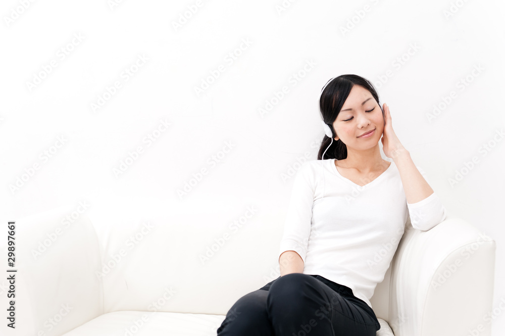 beautiful asian woman listening music on the couch