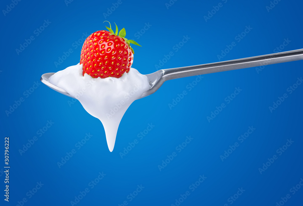 Spoon of natural yogurt with strawberry fruit on top over blue background