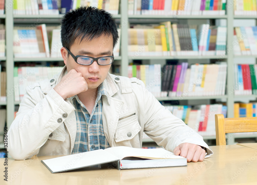 Handsome man sitting and reading in library