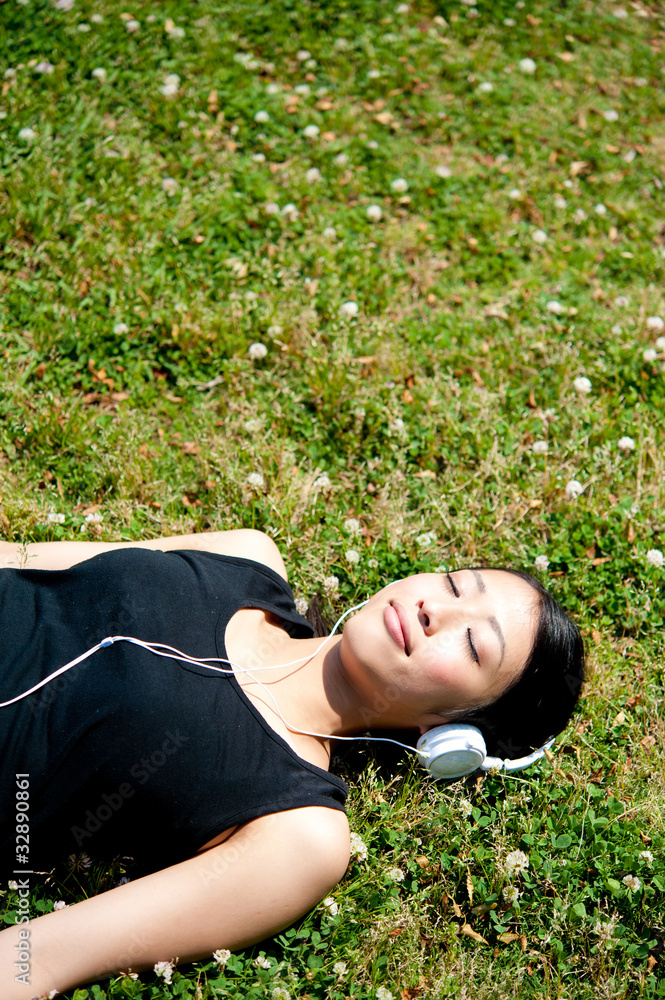 beautiful asian woman listening music in the park