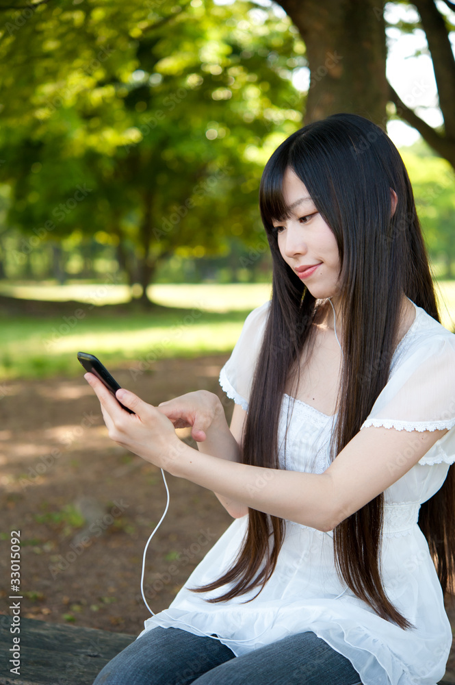 beautiful asian woman using a smartphone in the park