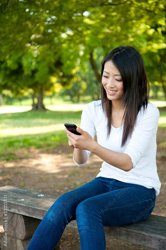 亚洲美女在公园里使用智能手机