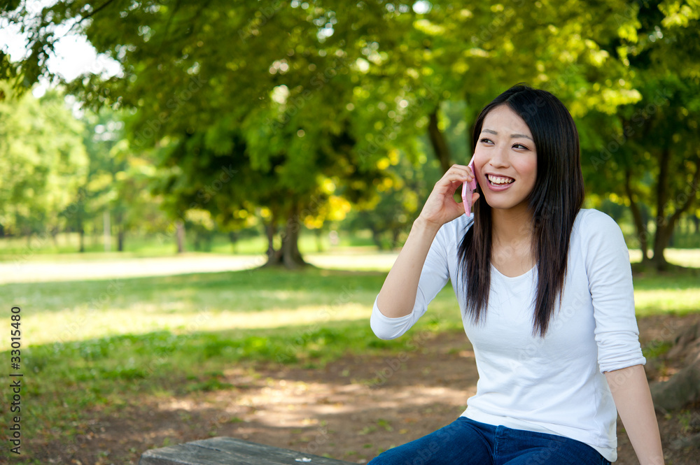 beautiful asian woman using cellphone in the park