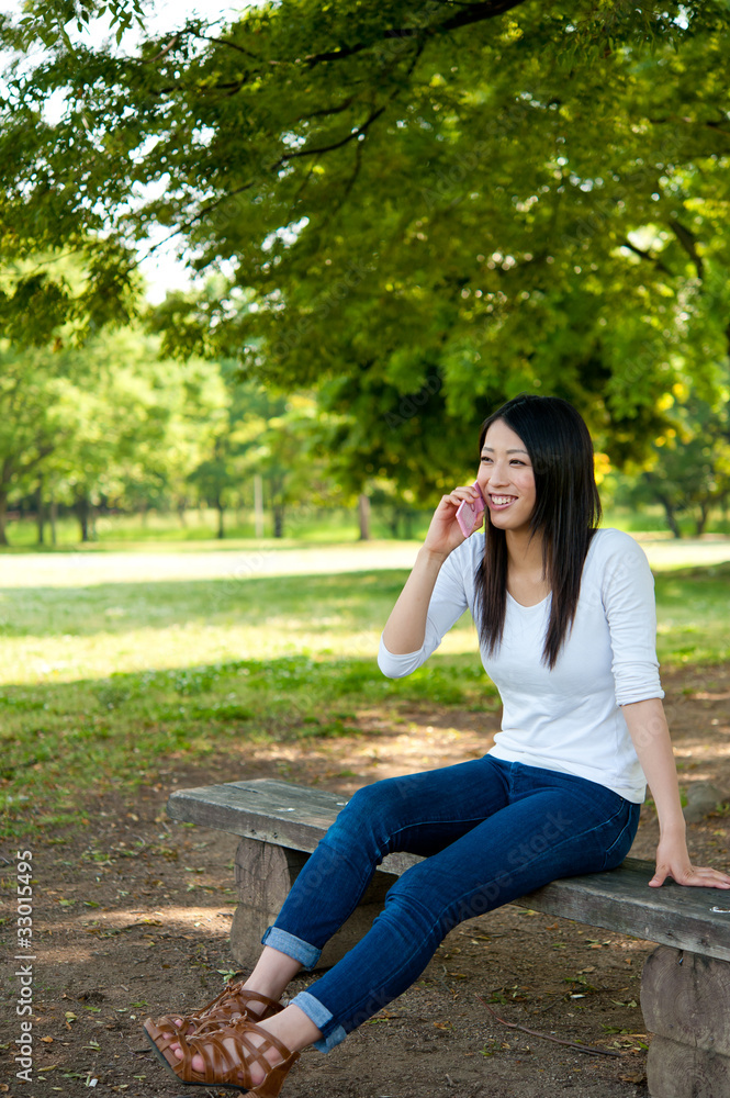 beautiful asian woman using cellphone in the park