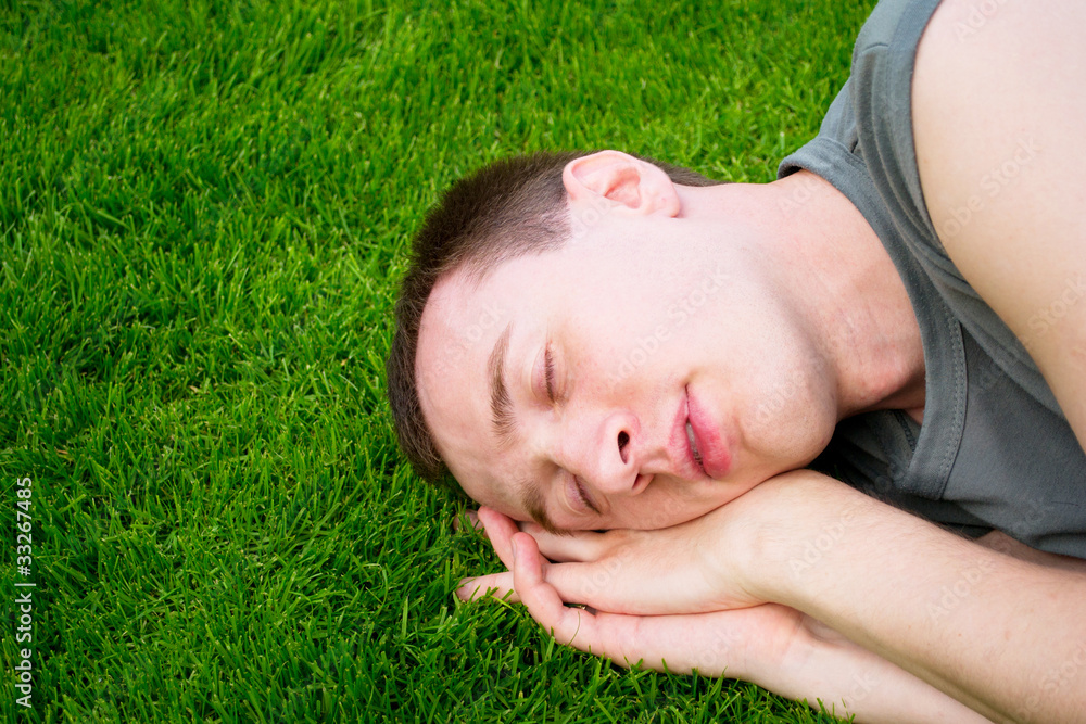 The young man sleeps on a green grass