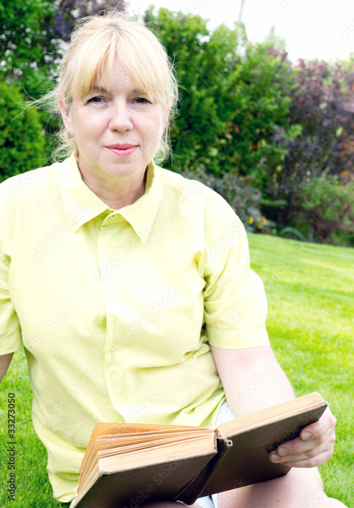 The woman reads the book on a lawn