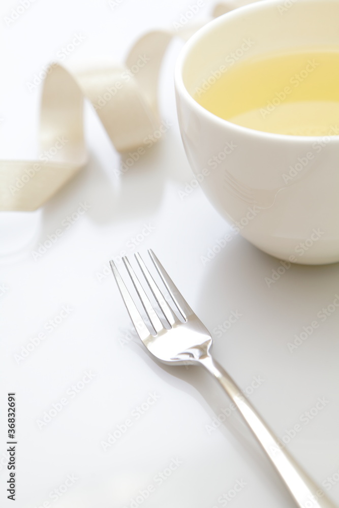 metal fork with a cup of green tea and ribbon