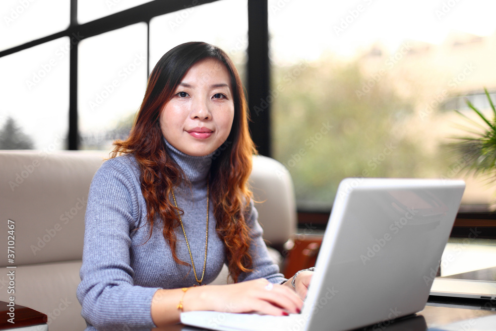 带着笔记本电脑微笑的亚洲商务女性