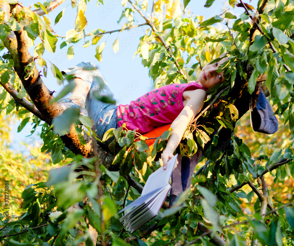 Mädchem auf dem Baum mit enem Buch