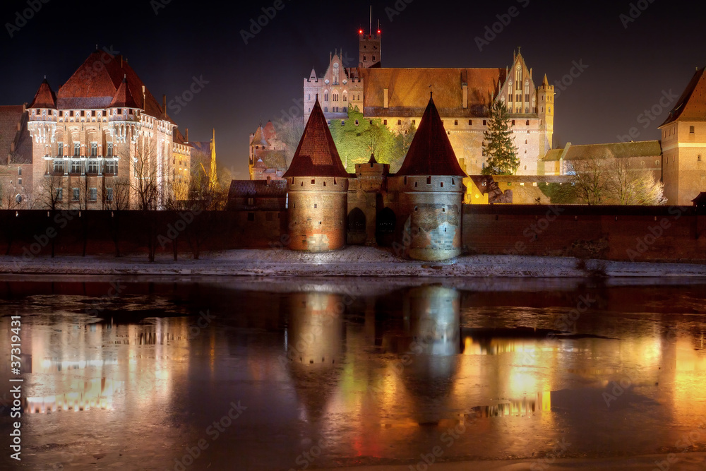 Malbork castle in Poland at night with reflection in Nogat river