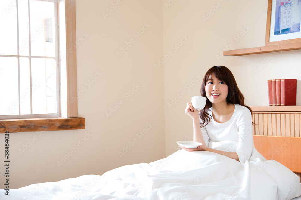 attractive asian woman drinking on the bed