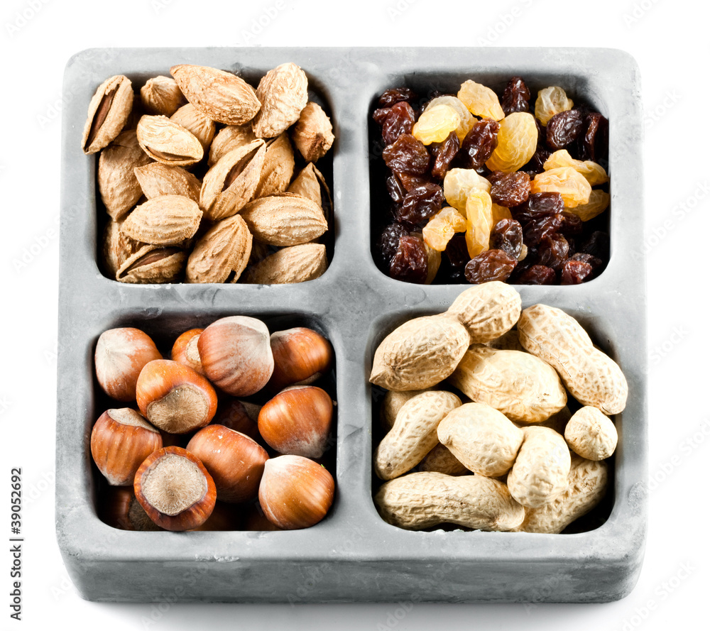 Varieties of nuts in plate: peanuts, hazelnuts, almond, raisins