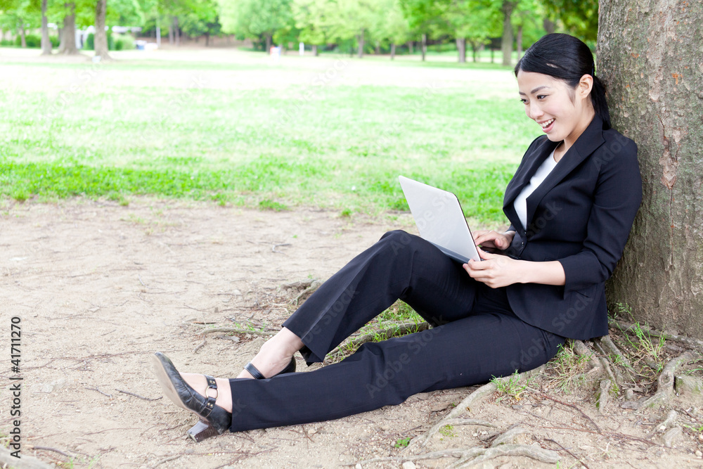 asian businesswoman using laptop in the park