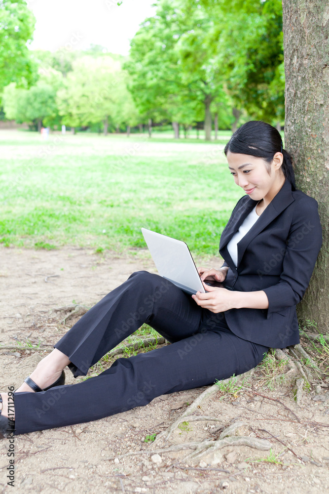 asian businesswoman using laptop in the park