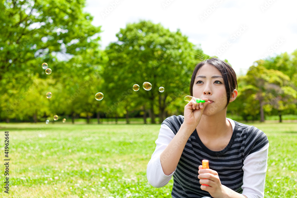 young asian woman with soap bubble in the park