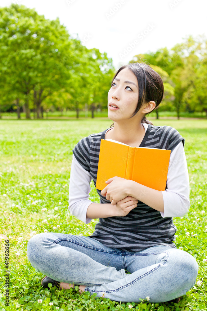 young asian woman reading book in the park