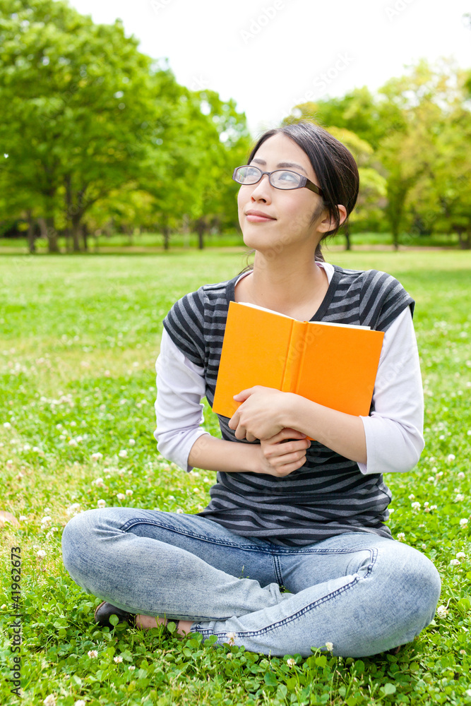 young asian woman reading book in the park