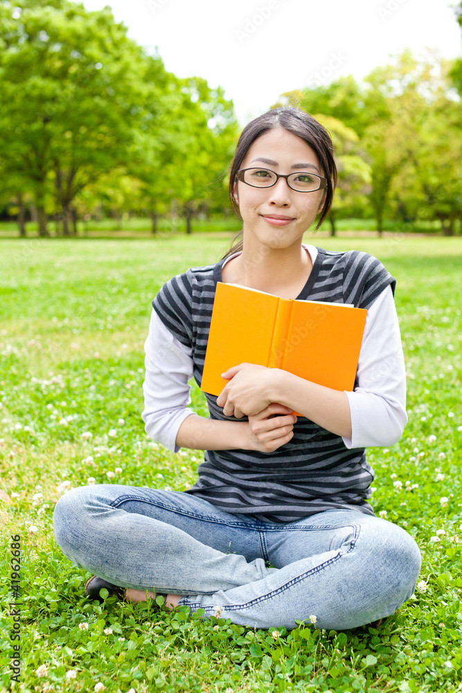 young asian woman reading book in the park