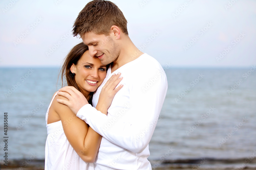 Couple Cuddling at the Beach Looking Happy