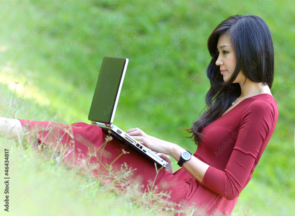 pretty  woman with laptop on green grass at the garden