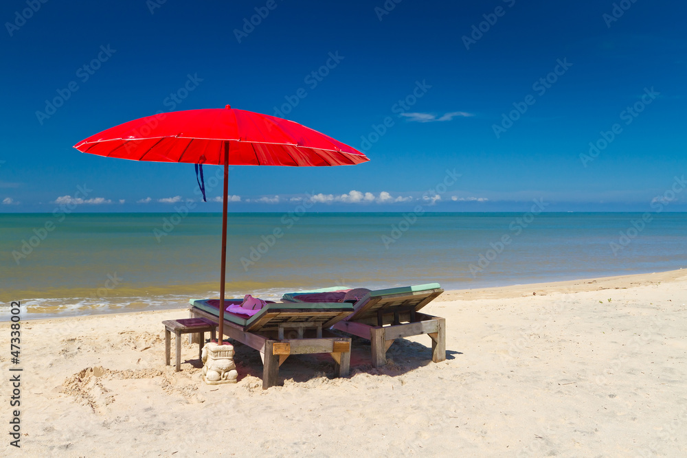 Red parasol with deckchair on tropical beach in Thailand