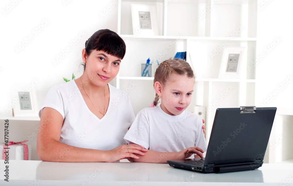 Mom and daughter are working together for a laptop