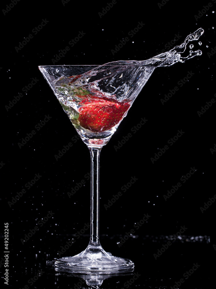 Martini drink splashing out of glass on black background