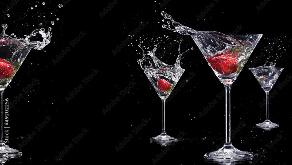 Martini drinks with splashes, isolated on black background