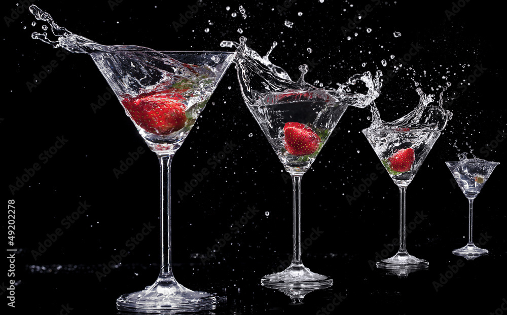 Martini drinks with splashes, isolated on black background