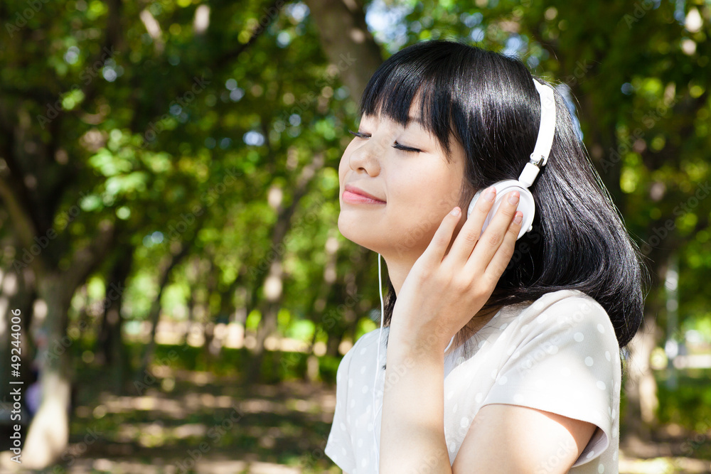 活跃的亚洲女人在公园里听音乐