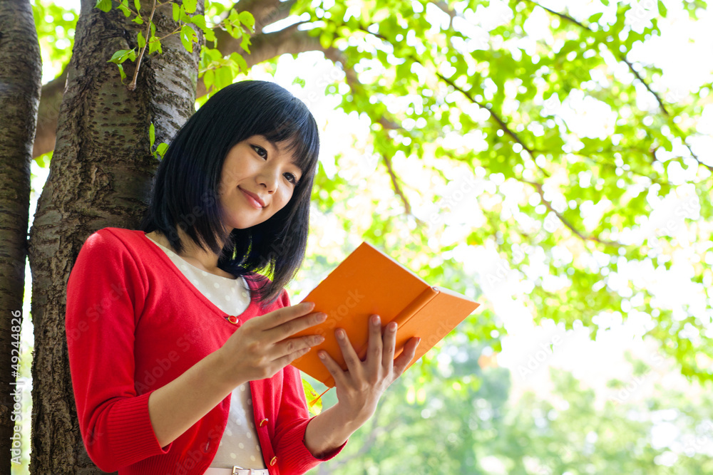 一个活跃的亚洲女人在公园里看书