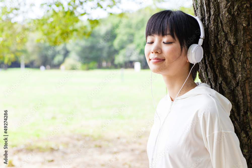 attractive asian woman listening music in the park