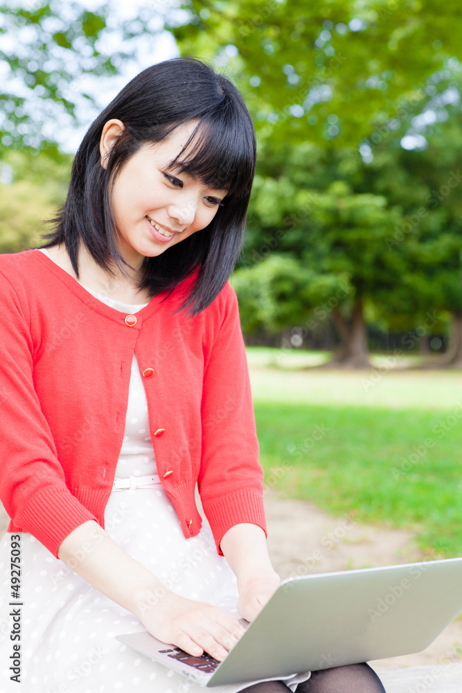 在公园里使用笔记本电脑的魅力亚洲女性