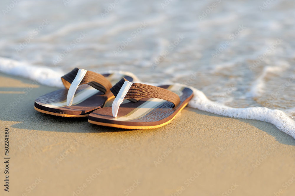 Flip flops on a sandy ocean beach