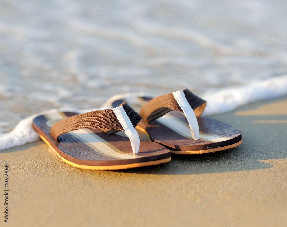 Flip flops on a sandy ocean beach